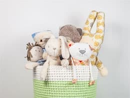 Много игрушек в двухцветной большой корзине.